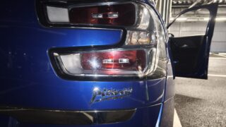 MVIMG_20260427_211045 – mbFAST Tuning Close-up of a blue car's rear tail lights with the trunk area, a partially open door, and a garage background.