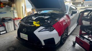 1778838507293 – mbFAST Tuning White luxury sedan in a shop with its hood up and engine exposed, tools placed over the front area, cables nearby.