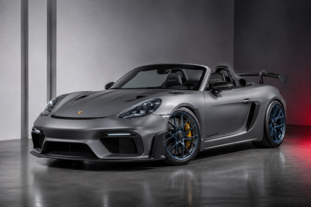 Silver Porsche 911 Spyder RS with blue aftermarket wheels and yellow brake calipers in a studio setting