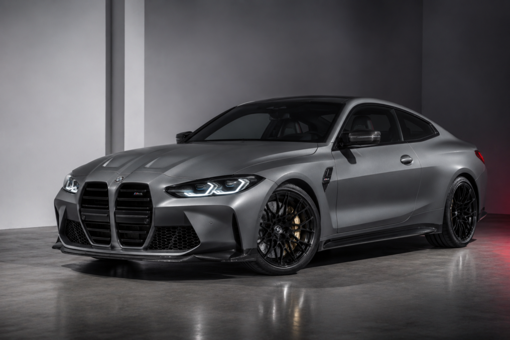 Grey BMW M4 coupe in a studio setting with aggressive front fascia and black multi‑spoke wheels