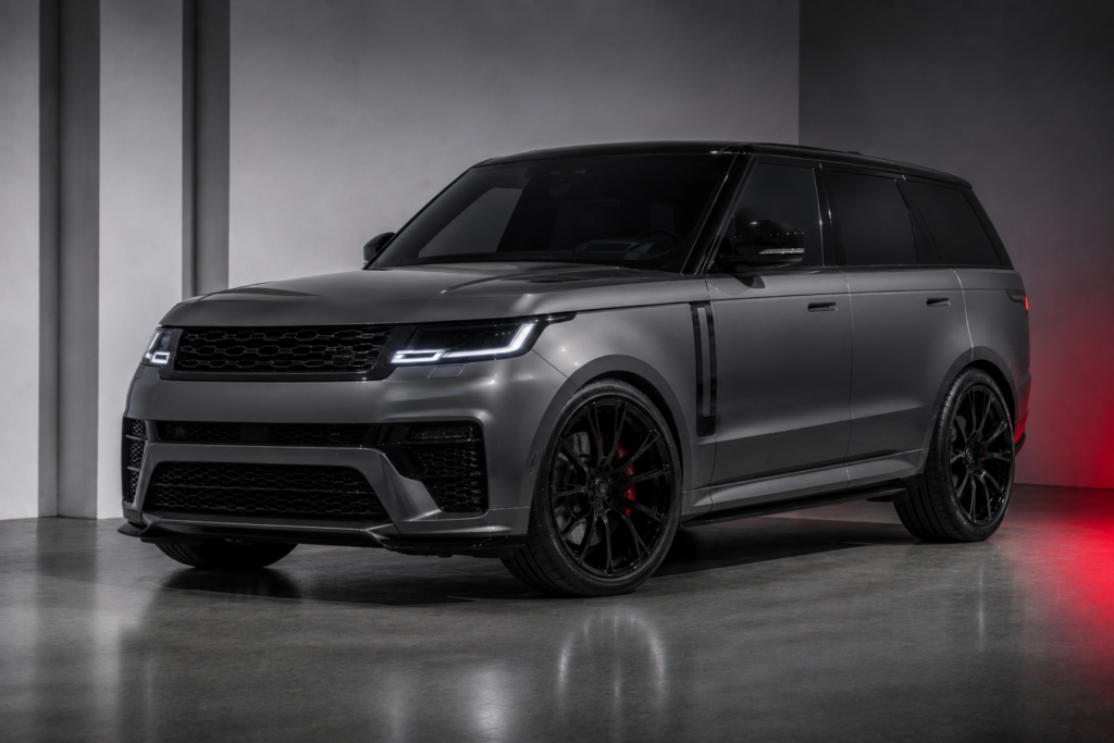 Three-quarter front view of a gray luxury SUV with dark windows, large black wheels, and red brake calipers in a showroom.