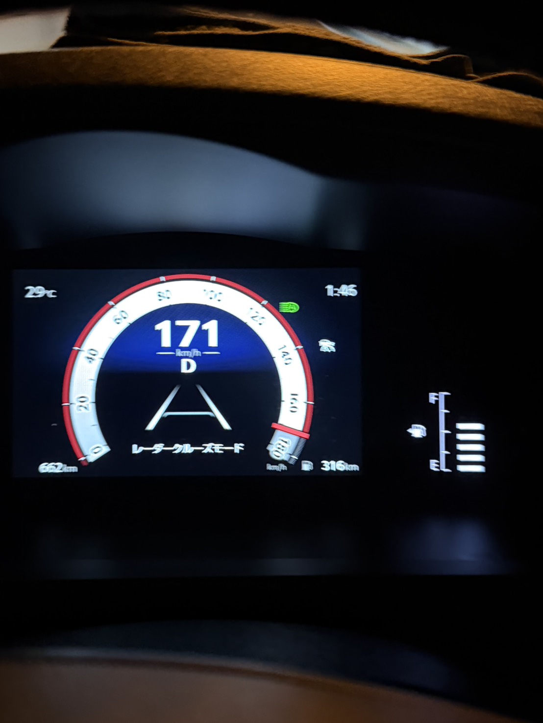 Digital car dashboard showing 171 km/h in large white numerals, gear in Drive (D) with a circular speedometer gauge edged in red, and Japanese text below; left shows outside temperature 29°C, right time 1:46, dashboard icons visible in dark interior.