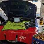 BMWのエンジンルームを開けて診断機とノートPCを接続しDMEロック解除の準備をしている様子