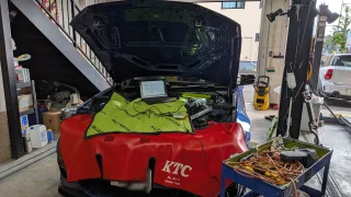 BMWのエンジンルームを開けて診断機とノートPCを接続しDMEロック解除の準備をしている様子