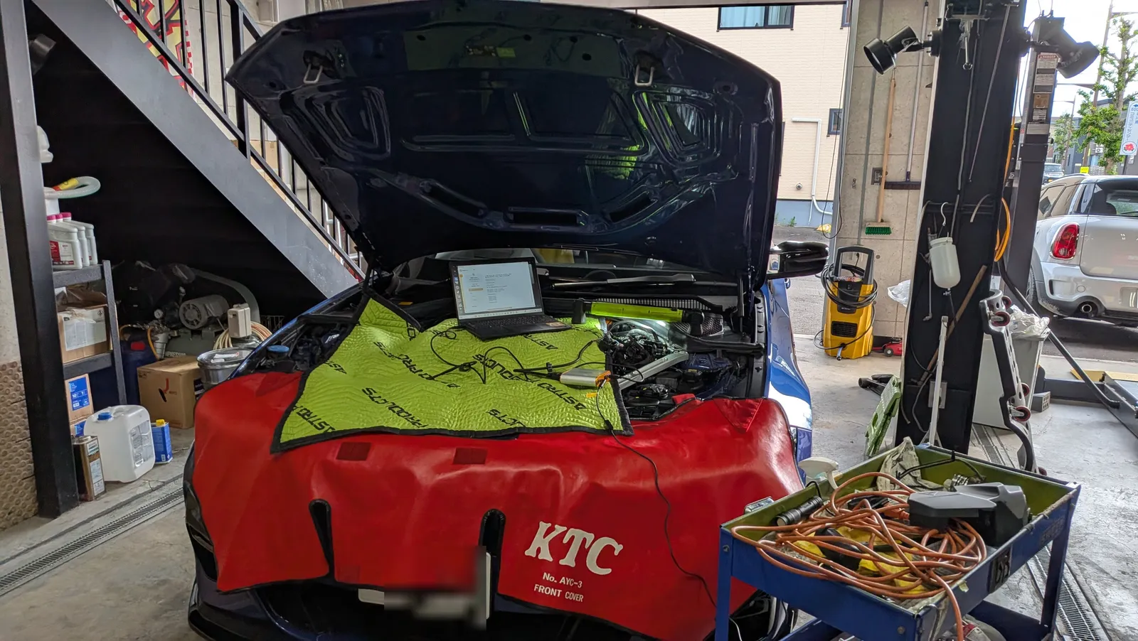 BMWのエンジンルームを開けて診断機とノートPCを接続しDMEロック解除の準備をしている様子