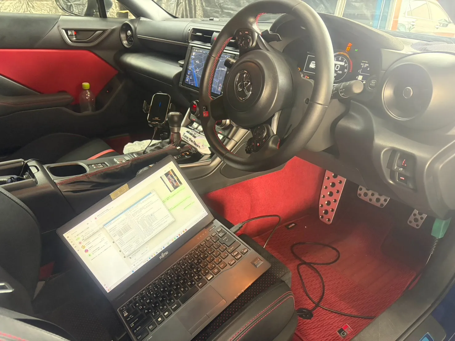 GR86の運転席にノートパソコンを接続してECUチューニングの書き込み作業を行っている様子