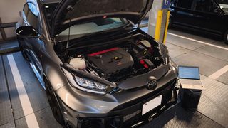IMG_20260810_182326 1 – mbFAST Tuning Grey SUV with its hood open, exposing the engine, in a vehicle inspection bay; a laptop sits on a stand nearby as a technician works.