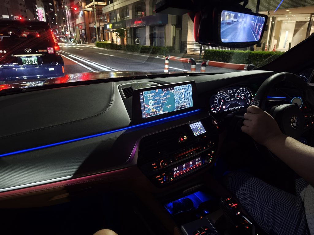 夜の市街地で施工後の実走確認を行う車内からの様子。ダッシュボードとナビ画面が見える