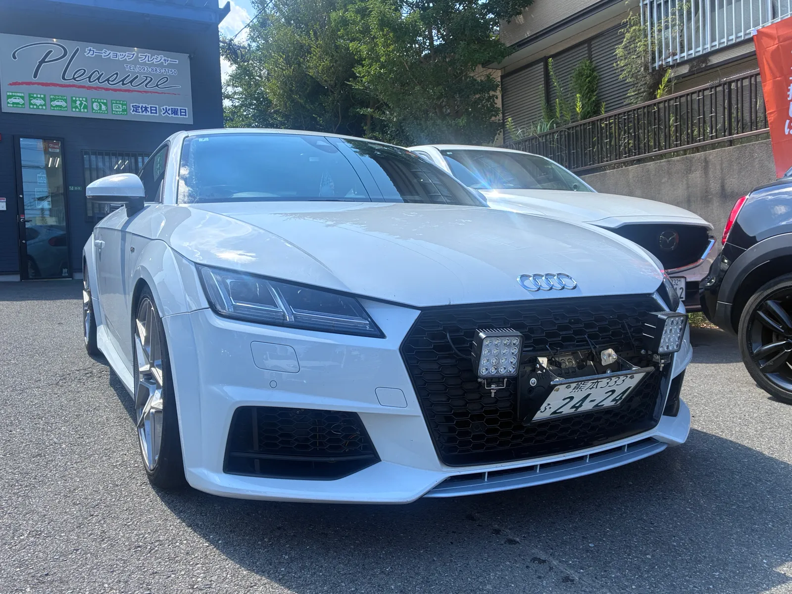 audi-tt-8s-bubbling-tuning-1 – mbFAST Tuning White Audi sports car front view with honeycomb grille and aftermarket LED light panels, Japanese license plate visible in a parking lot.
