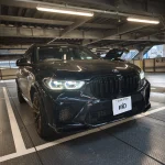 Front view of a black BMW SUV parked in a dim parking garage, showing prominent kidney grille and LED headlights.
