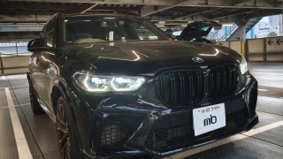 Front view of a black BMW SUV parked in a dim parking garage, showing prominent kidney grille and LED headlights.