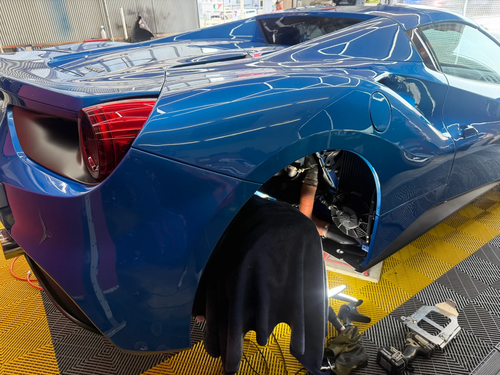 フェラーリ488スパイダーのリアフェンダー内でECU関連作業を行っている様子