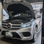ボンネットを開けたMercedes-Benz GLS350dのエンジンルームを確認している様子