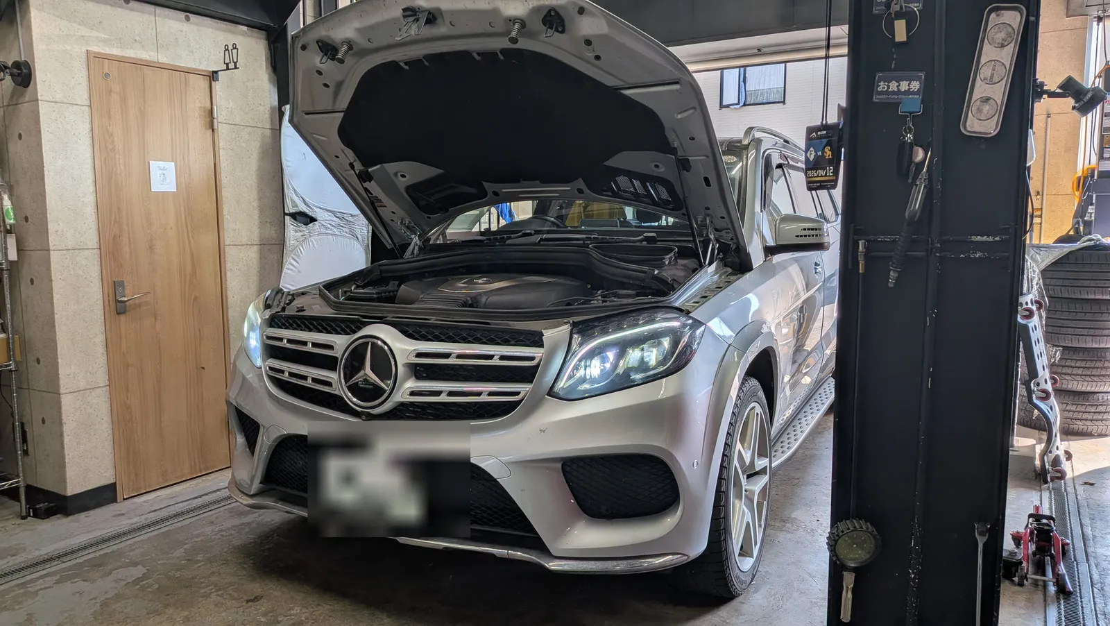 ボンネットを開けたMercedes-Benz GLS350dのエンジンルームを確認している様子