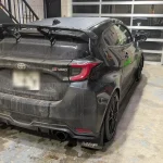 泥はねの残るTOYOTA GRヤリスのリアビュー。カーボンリアスポイラーとGR-FOURバッジが確認できる