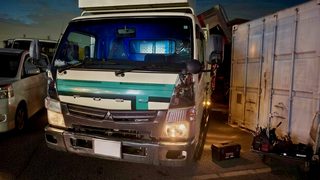 image – mbFAST Tuning Front view of a white delivery truck with teal stripe, parked in a lot beside a large white container.