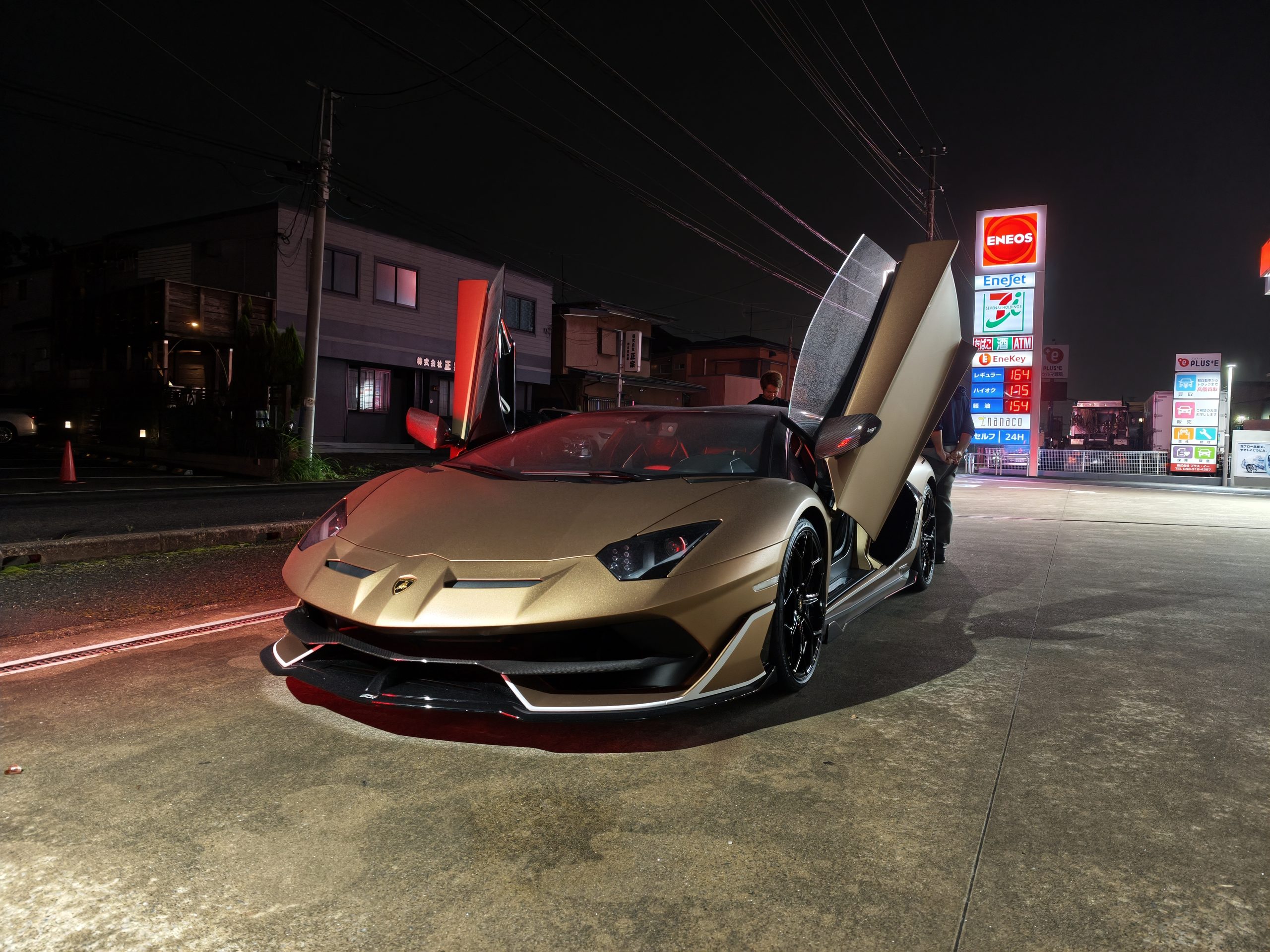 夜のガソリンスタンドでドアを開けたランボルギーニ アヴェンタドールSVJ
