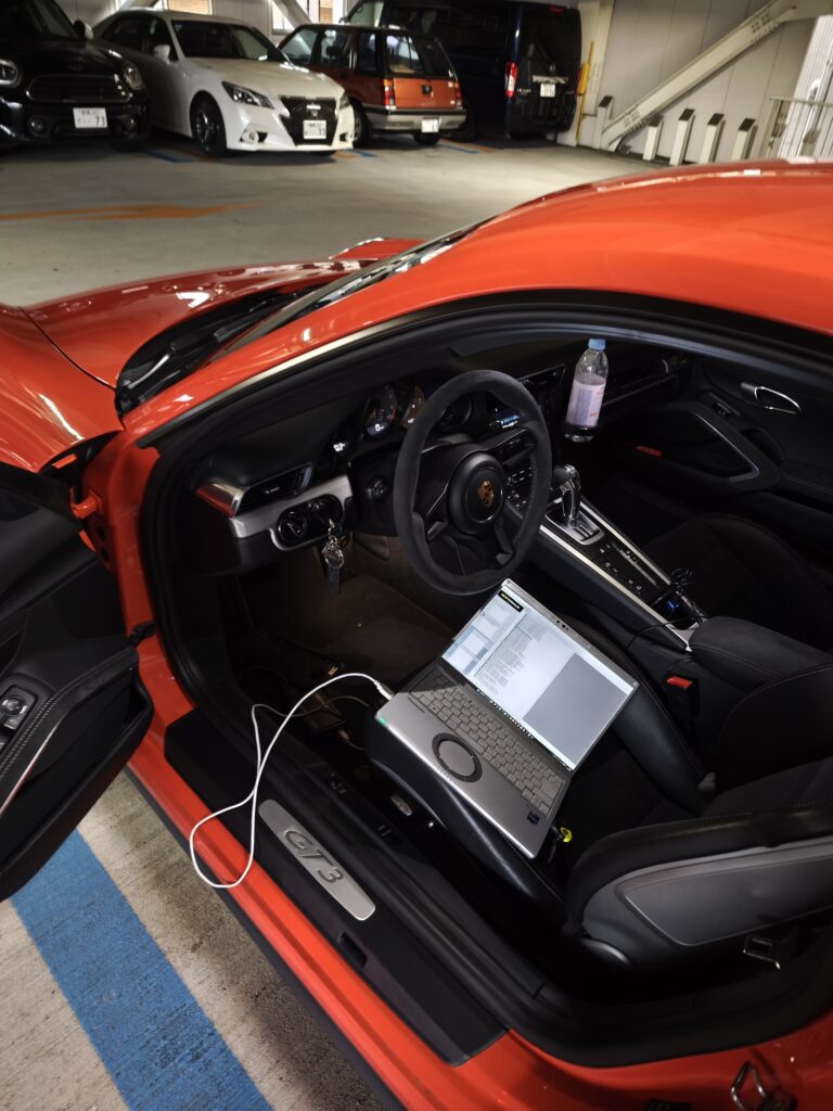 ポルシェ 991 GT3の運転席にノートPCを接続し、OBDからECUチューニングの書き込みを行っている様子
