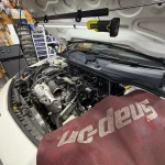Aクラスのエンジンルームを開けてサーモスタット交換作業を行っている様子