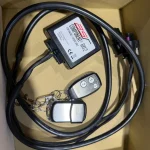 Automotive wiring kit with a small black control module labeled 'Component RX2', thick cables, and a two-key fob in a box.