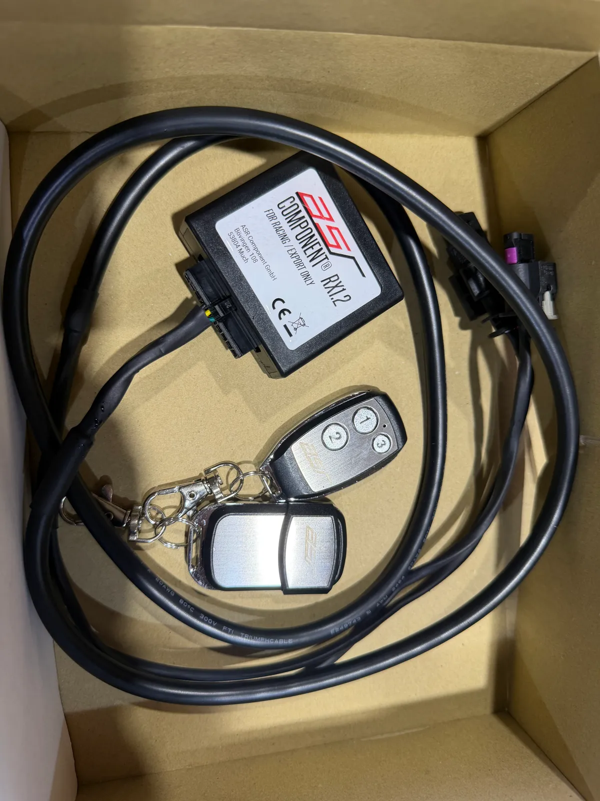 a35amg-asr-valve-control-1 – mbFAST Tuning Automotive wiring kit with a small black control module labeled 'Component RX2', thick cables, and a two-key fob in a box.