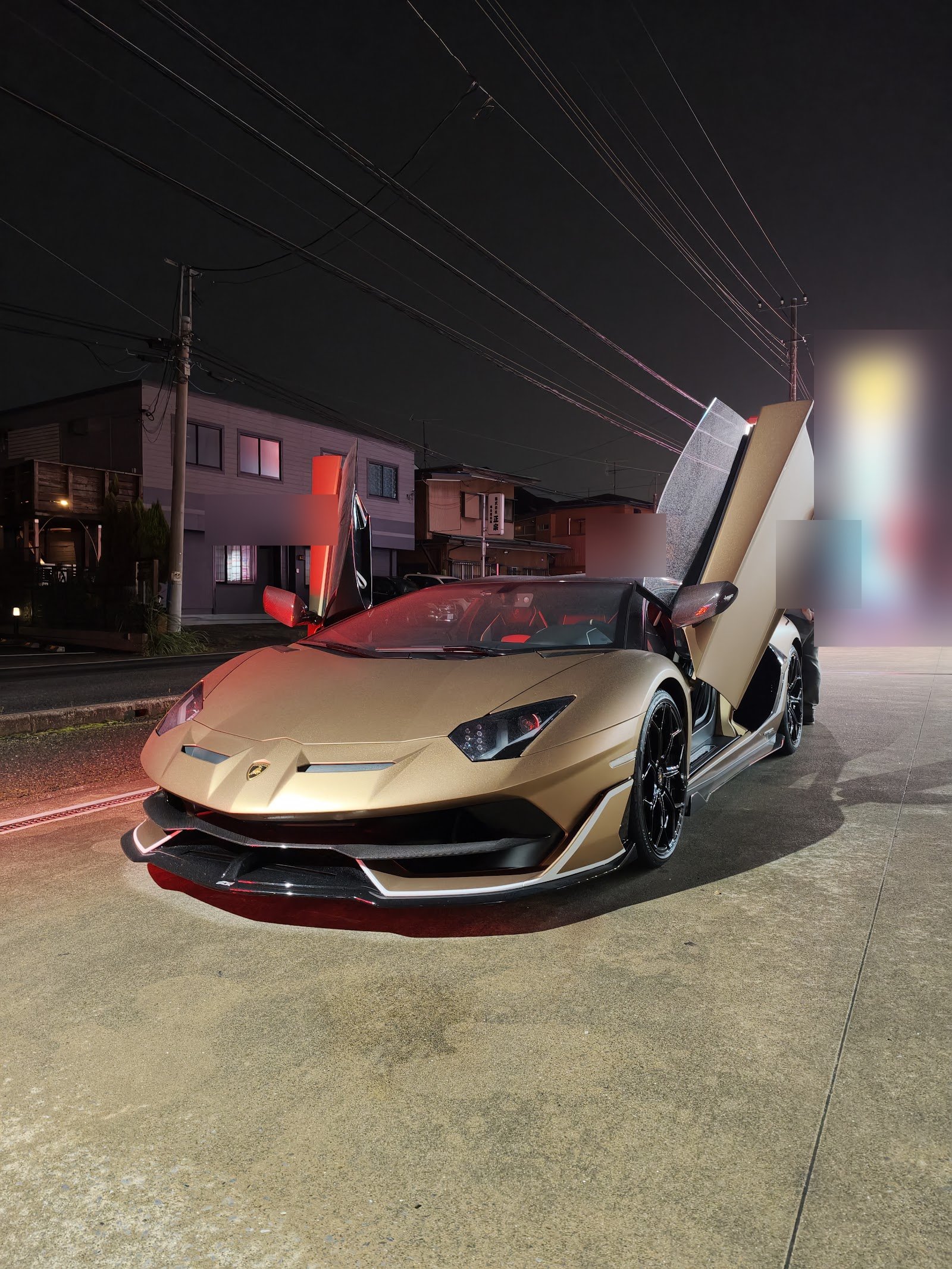 aventador-svj-obd-flash-hero – mbFAST Tuning Gold Lamborghini with scissor doors open, parked on a city street at night, red interior glow visible.