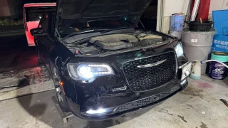 chrysler300c-radiator-replacement-1 – mbFAST Tuning ボンネットを開けたクライスラー300Cのエンジンルームとヘッドライト点灯の様子