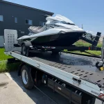 トレーラーに積載されたジェットスキーを積載車で搬送している様子