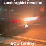 Nighttime street scene with a dark sport motorcycle spewing a bright exhaust flame; text overlays read 'jobdesign Lamborghini revuelto' and 'ECU tuning'
