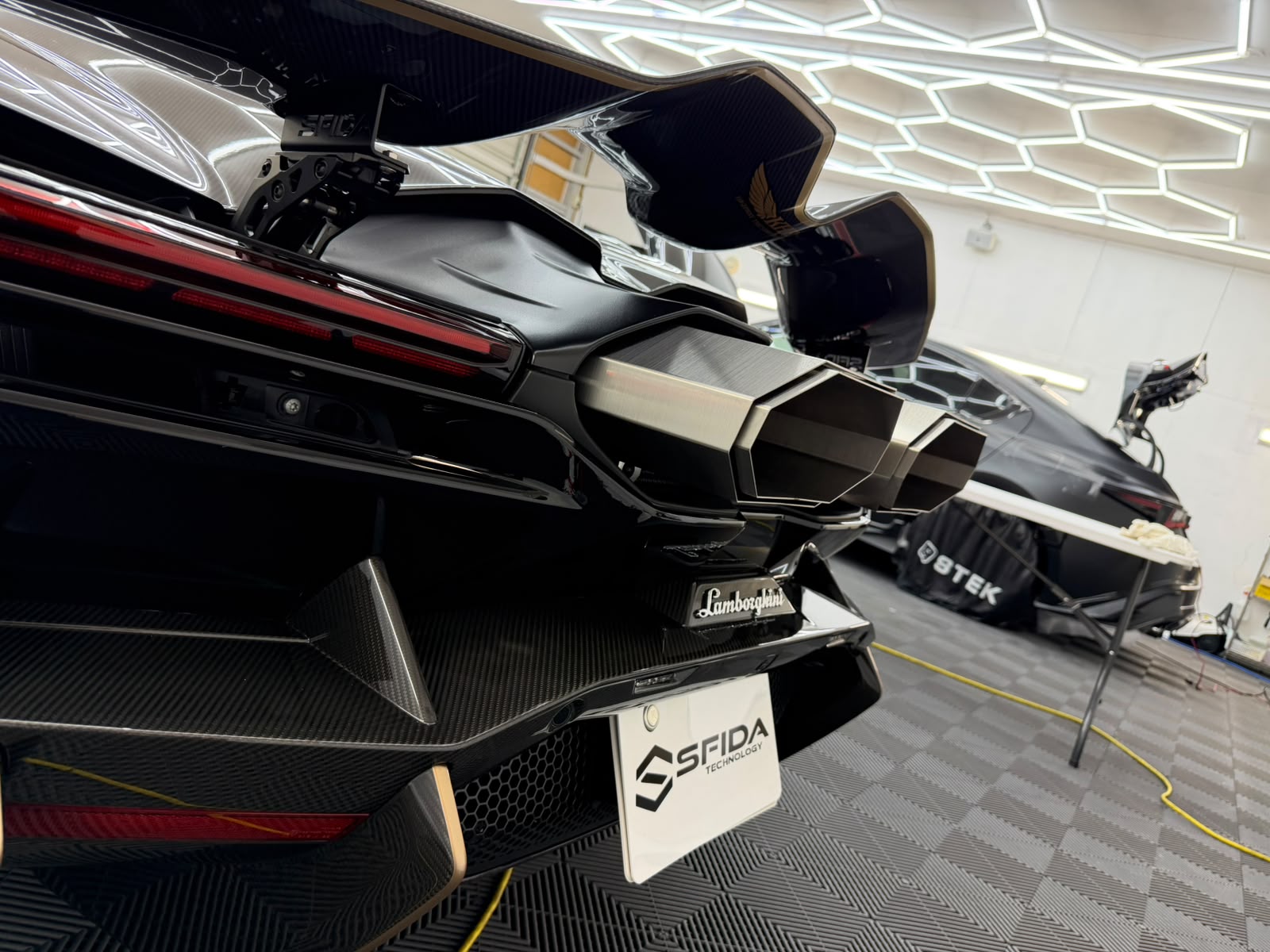 Close-up of the high-mounted hexagonal exhaust tips of a bla – mbFAST Tuning Close-up of the high-mounted hexagonal exhaust tips of a black Lamborghini Revuelto fitted with the SFIDA exhaust system
