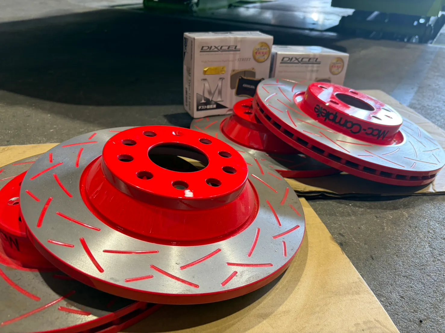 golf-gti7-brake-rotor-pad-replacement-2 – mbFAST Tuning 新品のスリット入りブレーキローターとDIXCEL製パッドの箱を並べたクローズアップ