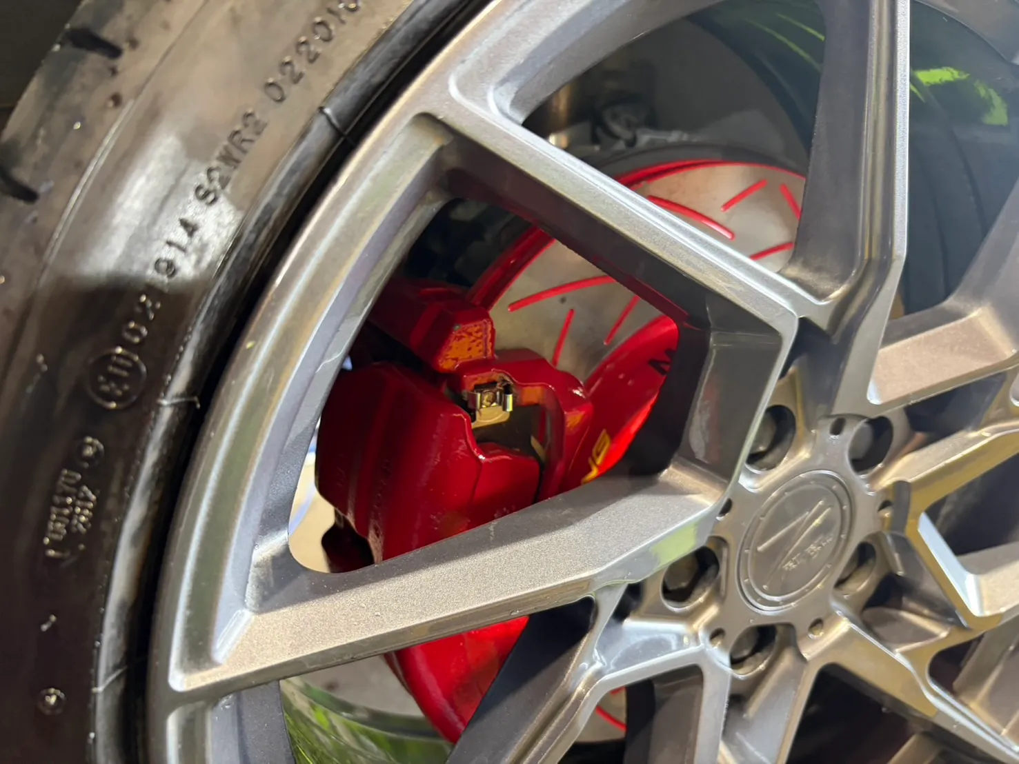 golf-gti7-brake-rotor-pad-replacement-7 – mbFAST Tuning ホイールスポークの間から覗く赤いキャリパーのクローズアップ