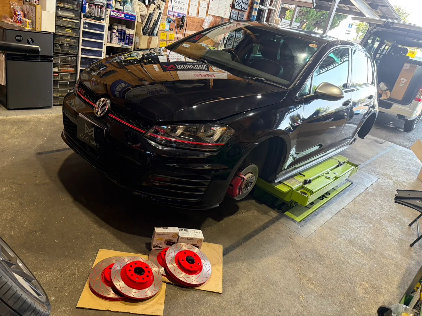 golf-gti7-brake-rotor-pad-replacement-8 – mbFAST Tuning 作業後の車両全体像と床に並ぶ交換前後のローター