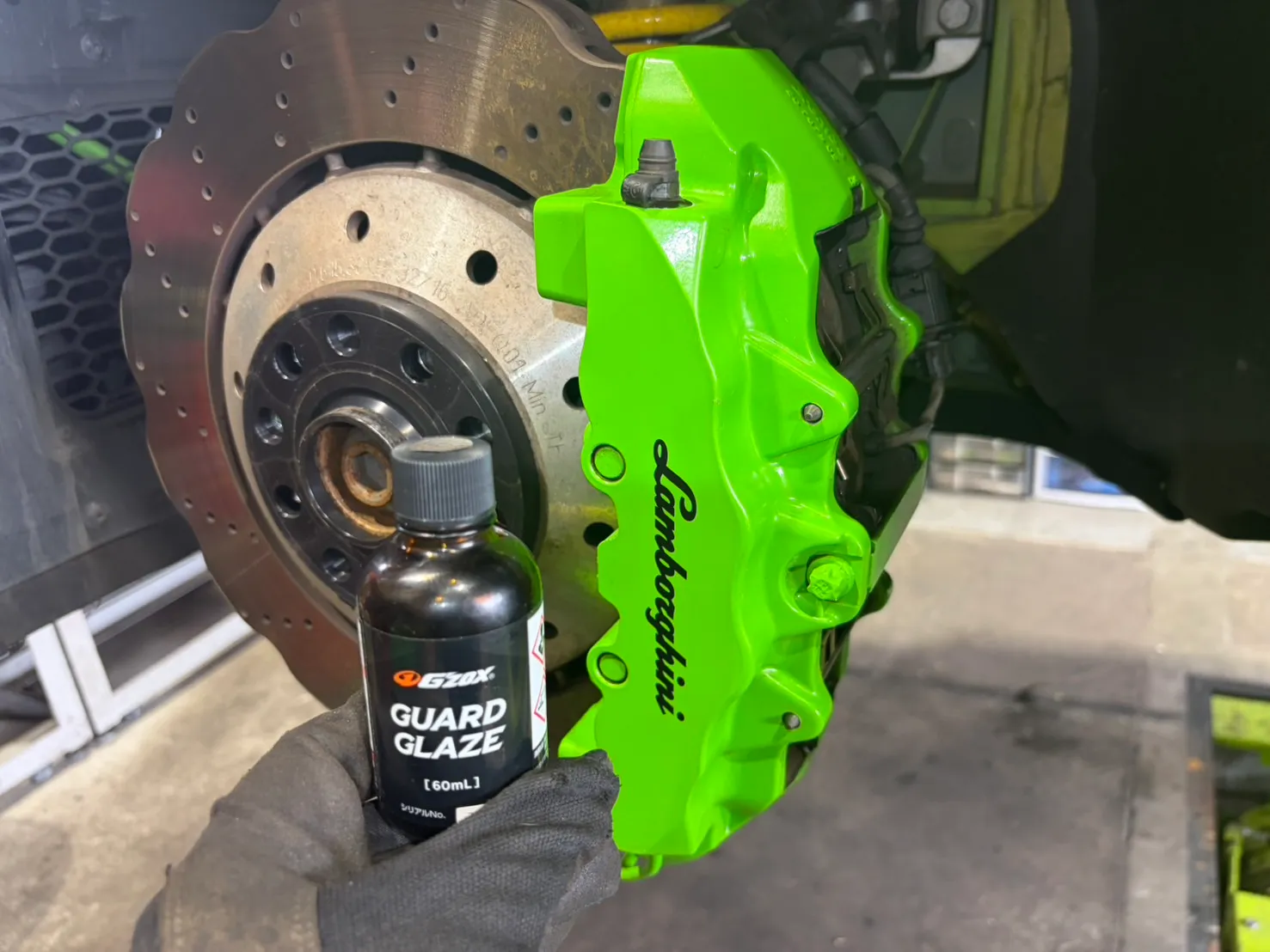 huracan-caliper-coating-3 – mbFAST Tuning コーティング剤のボトルとキャリパーを並べて確認している様子